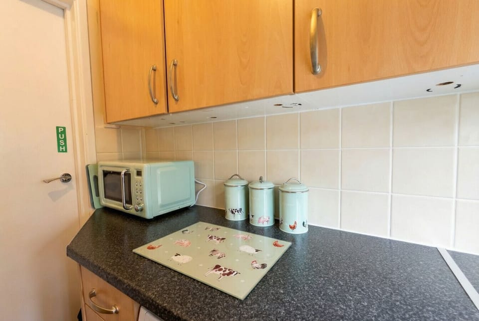 A vintage-style microwave and charming farmyard canister set add a homely touch to the kitchen.