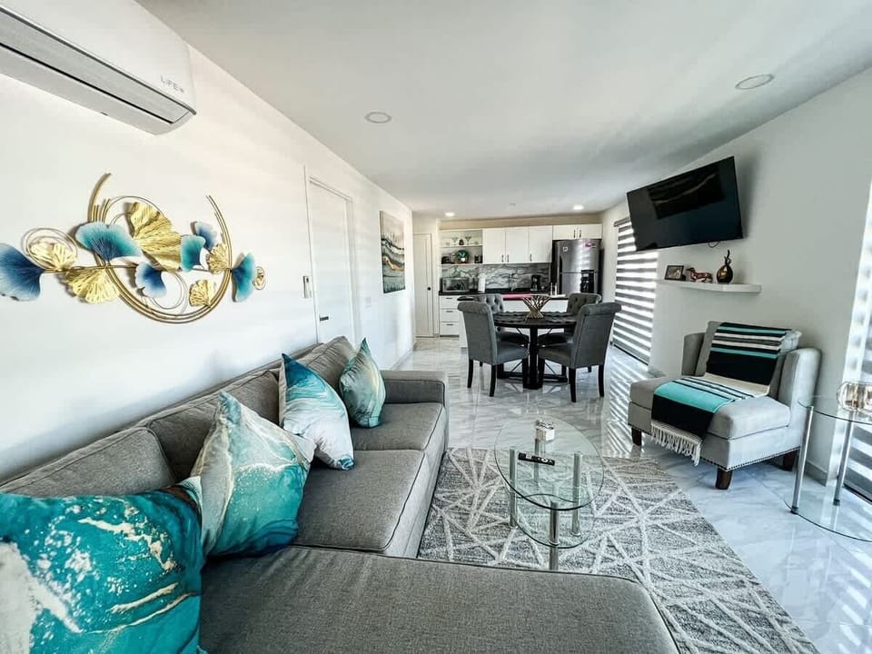 Bright living room w/ cozy seating, TV & large windows letting in natural light