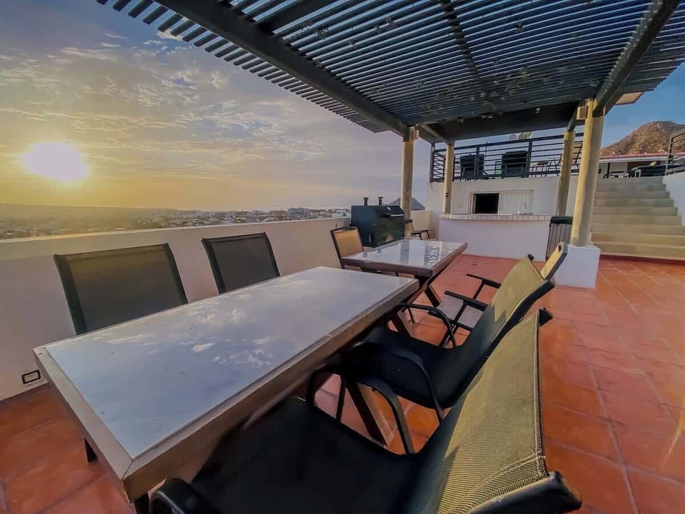 Shared rooftop dining area w/ long table, ideal for meals & sunset gatherings