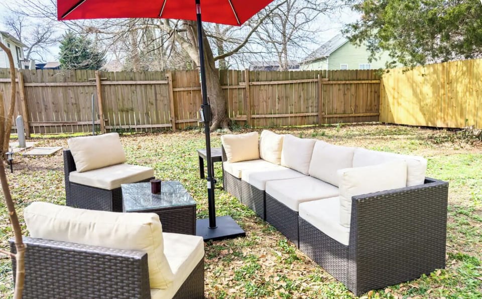 A large, fully fenced shared backyard with a patio and fire pit