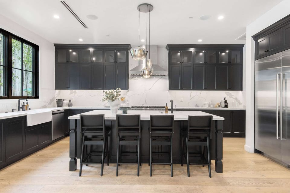 An oversized kitchen island designed for gathering, with seating, custom cabinetry, and premium appliances