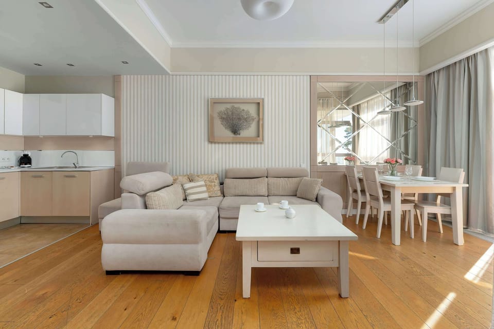A combined living and dining area with a sofa facing a coffee table and a dining table visible in the background. The open-plan layout creates a sense of space and functionality. Bright daylight enhances the clean and modern aesthetic.