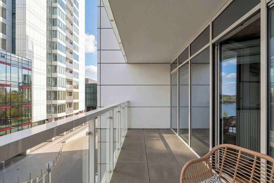 A view of the balcony's glass railing, showcasing the modern facade of the building and the street below.