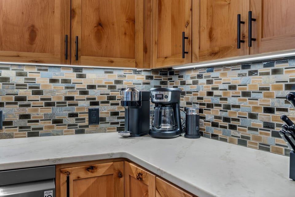 Start your mornings right with coffee brewing in this well-equipped kitchen, featuring warm wood cabinets and stylish tile backsplash.