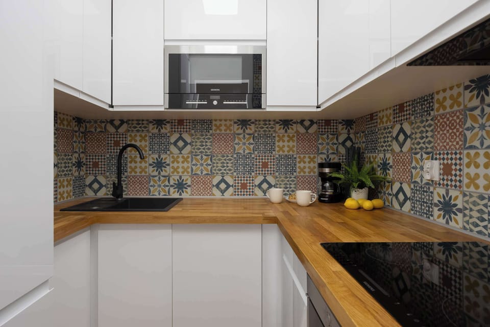 A corner view of the kitchen showing more workspace and storage. The colorful tiles create a stylish accent.