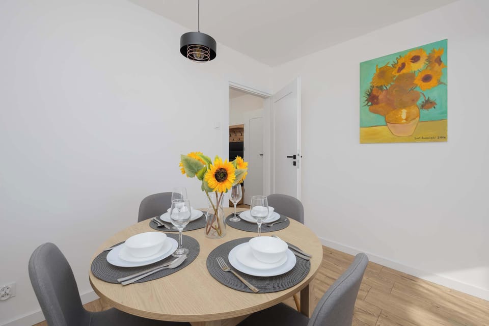 A small dining table set for two with simple decor. A vase with flowers adds a nice touch.