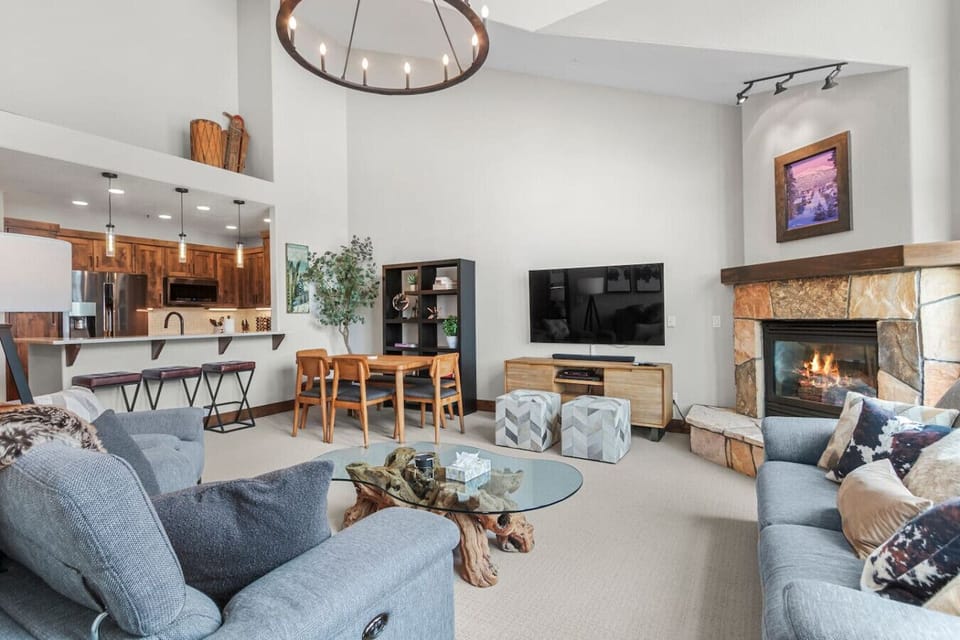 Spacious living room with vaulted ceilings, floor to ceiling windows, gas fireplace, and smart TV