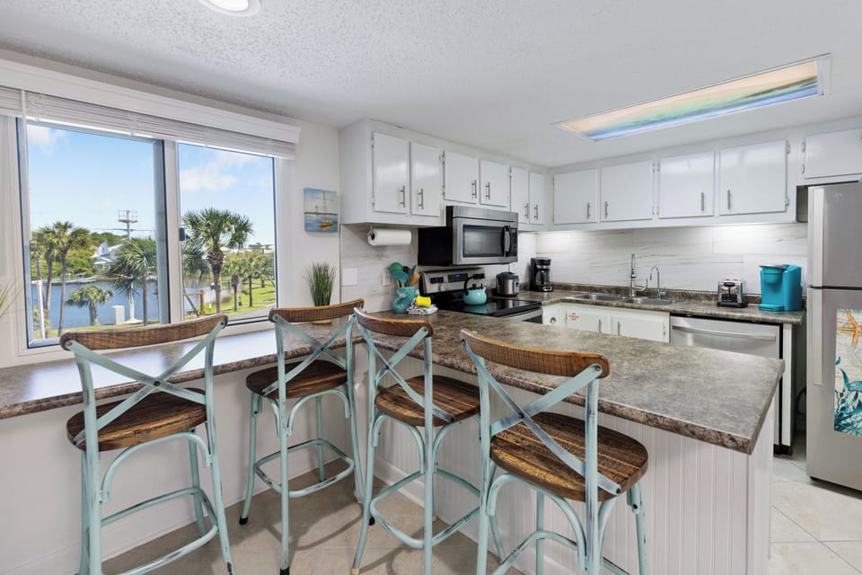Your bright kitchen features granite counters, modern appliances, and coastal charm with turquoise accents and tropical views.