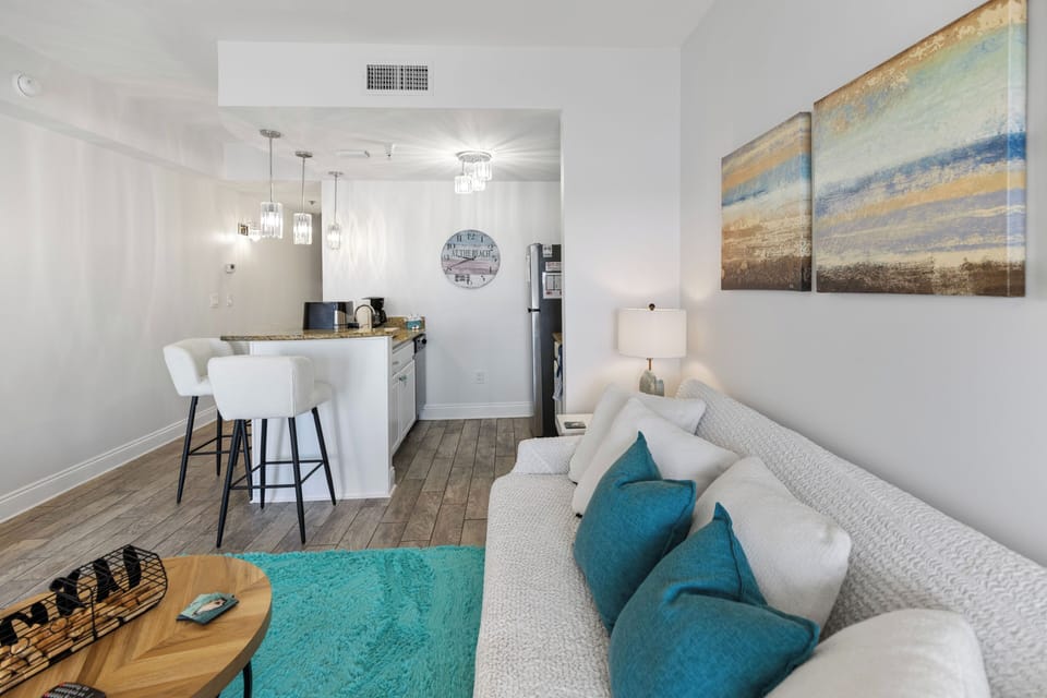 Sink into plush seating while turquoise accents add warmth to your bright, open-concept retreat with modern kitchen.