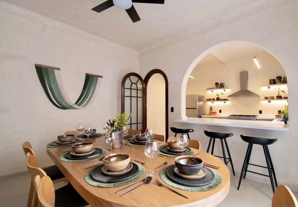 A thoughtfully set dining area designed for easy conversation and memorable meals. Warm wood tones, layered table settings, and a smooth connection to the kitchen create a space that feels both inviting and refined.