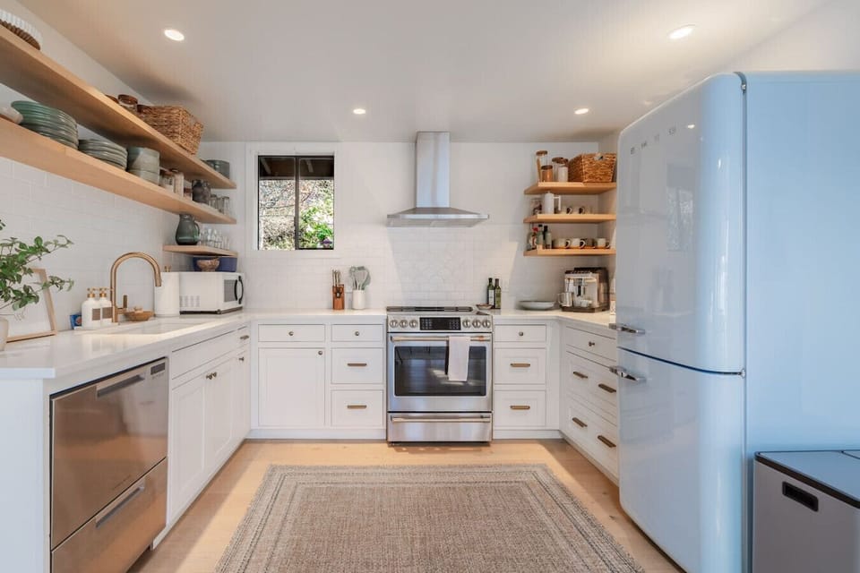 Fully equipped kitchen with gas range, dishwasher, open shelving, and that iconic retro blue fridge