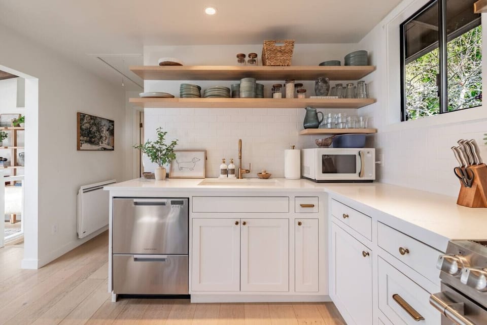 Well-stocked kitchen with open shelving, microwave, dishwasher, and plenty of counter space