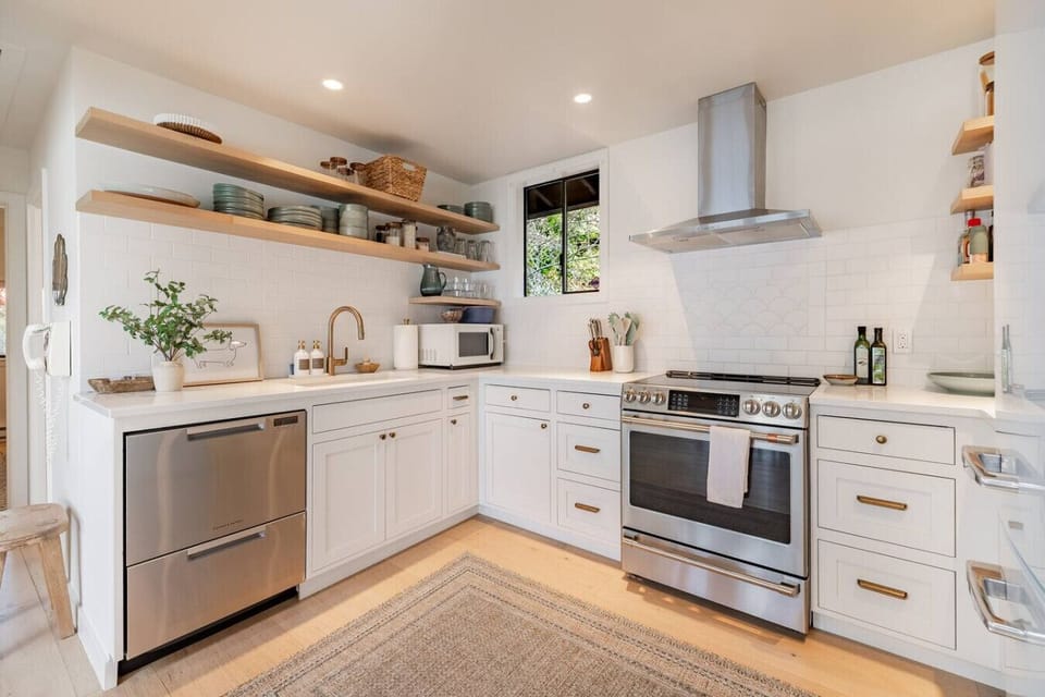 Fully equipped chef`s kitchen with stainless appliances, gas range, and open shelving