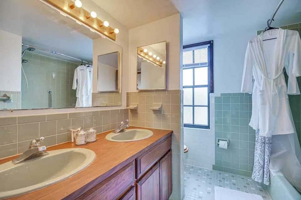 Bathroom with dual sinks, wooden vanity, and natural light from a window.