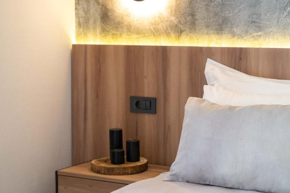 Stylish bedroom corner with warm lighting, modern décor, and a plug right next to the bed, designed to offer comfort and functionality