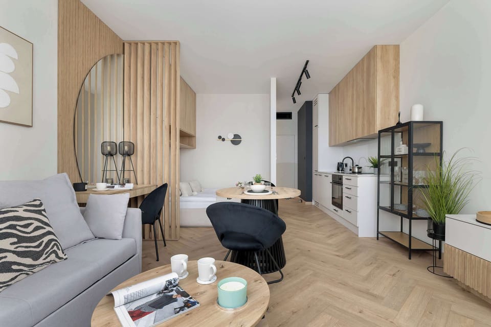A wider view of the open-plan space combining the living room and dining area. A round dining table with dark chairs sits near the seating area, giving the interior a modern and functional layout.