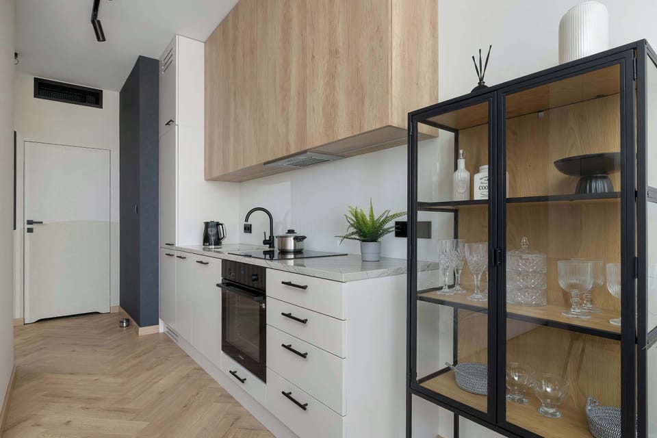 A kitchenette area with modern cabinetry and a glass-front display cabinet. The space is designed efficiently, combining functionality with a sleek, contemporary style.
