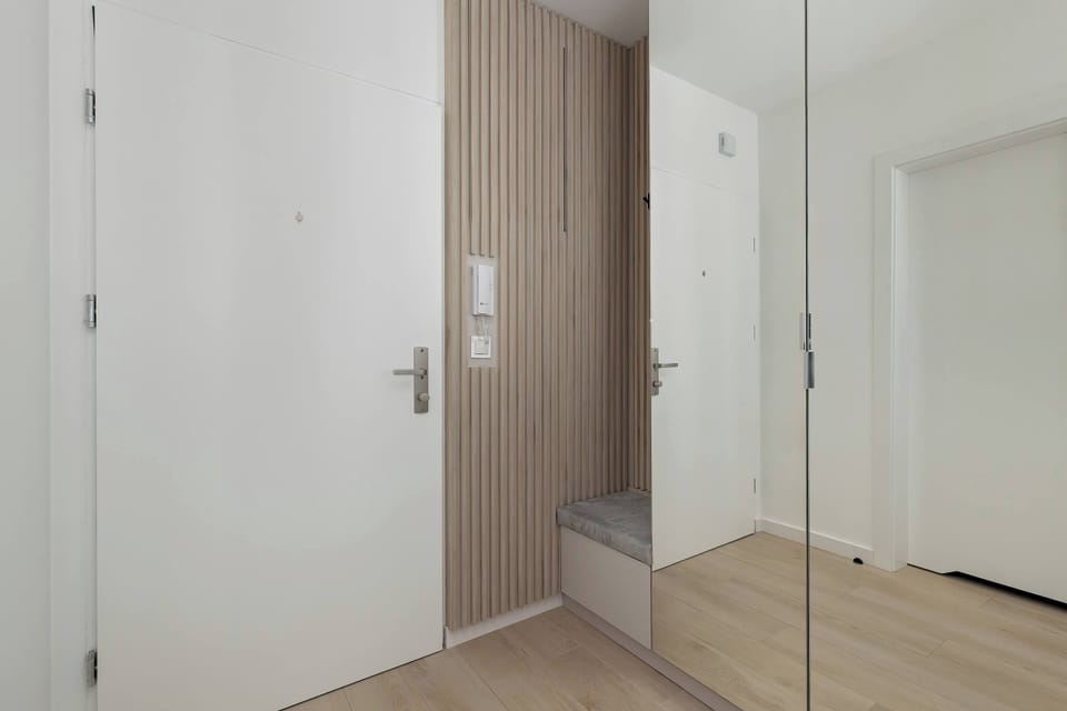 An entryway area featuring a large mirror and a white door, creating a sense of space and cleanliness upon arrival.