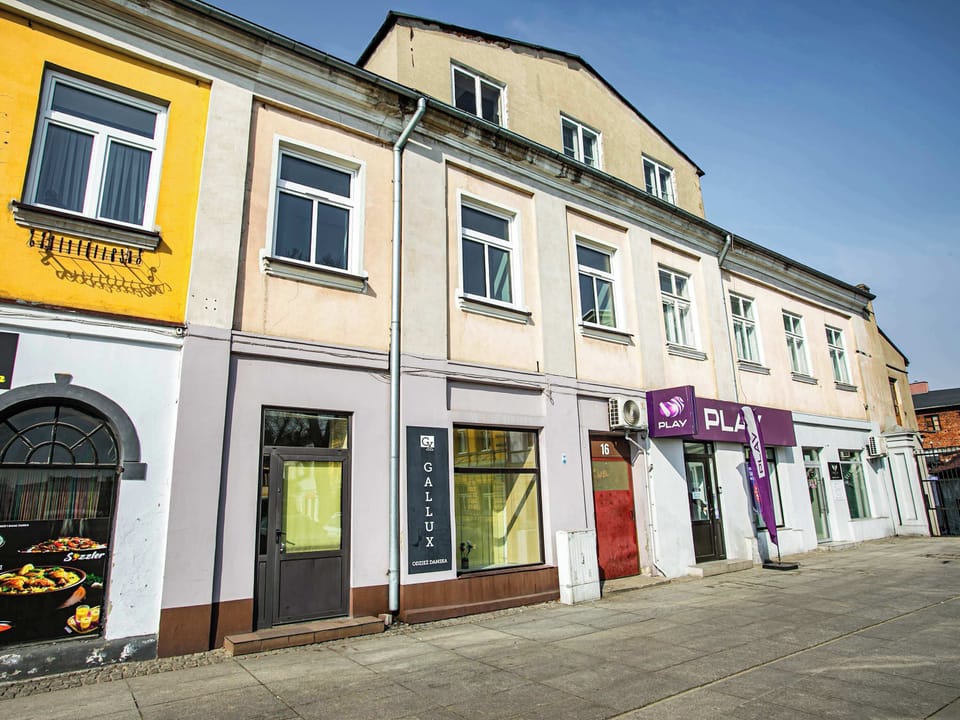A row of charming, colorful buildings with decorative facades and ground-floor shops. The architecture suggests a vibrant and well-maintained urban area.