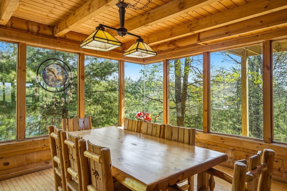Gather your group around this rustic dining table surrounded by floor-to-ceiling windows showcasing peaceful forest views in every direction.