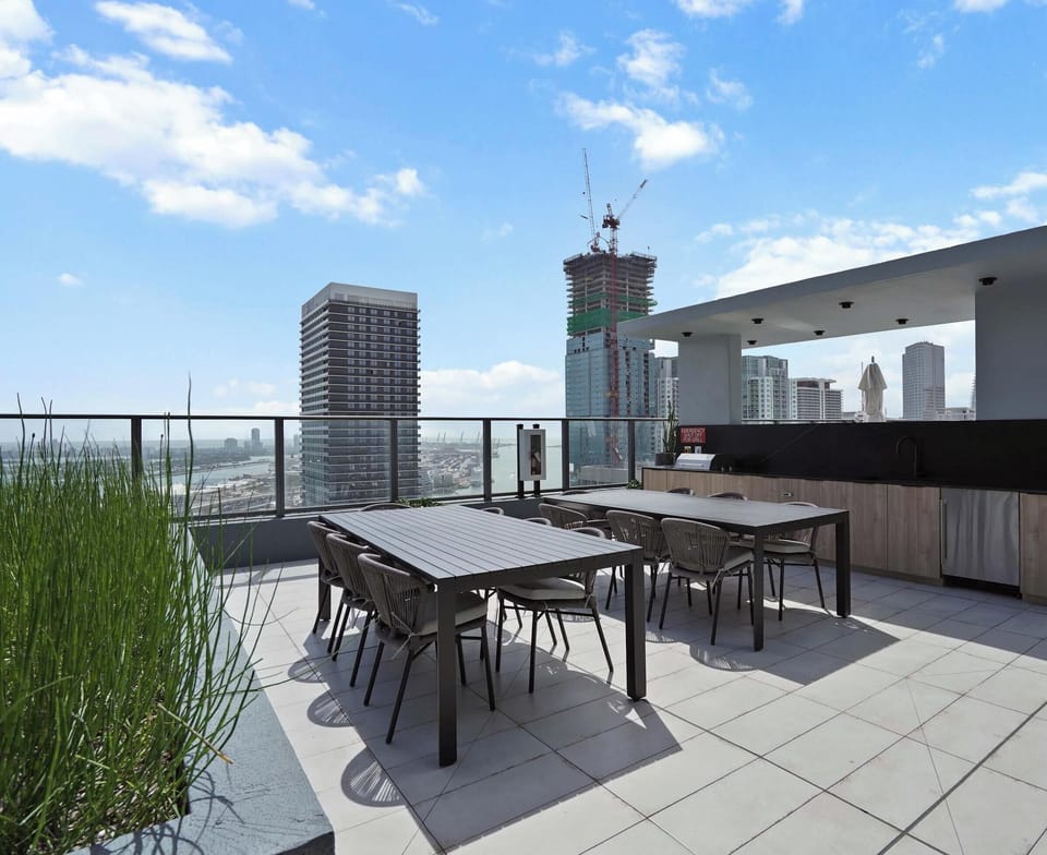 A spacious rooftop with lounge seating, with a backdrop of stunning city views.