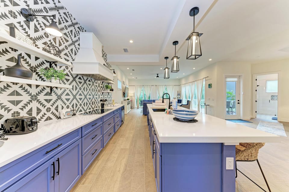 Cook gourmet meals in your stunning kitchen featuring navy blue cabinets, quartz countertops, and eye-catching geometric backsplash.