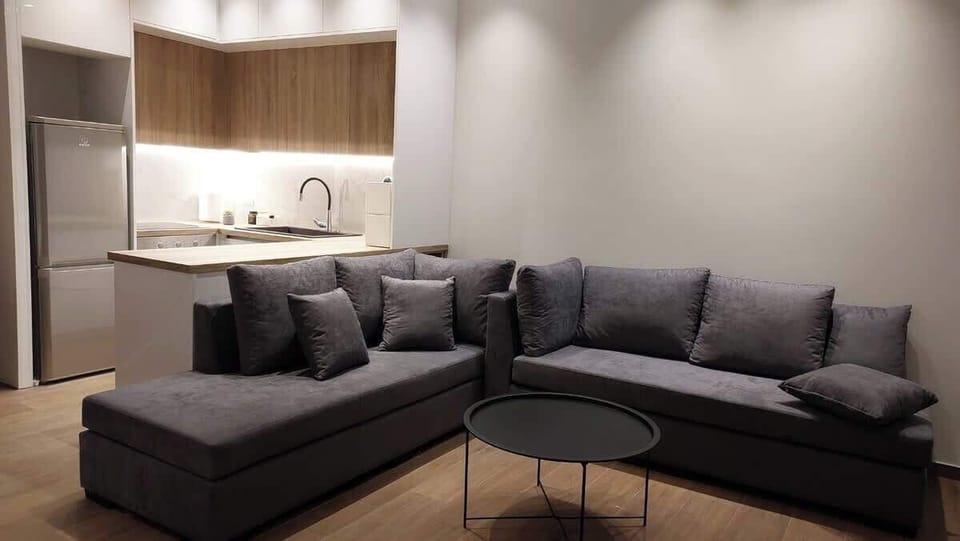 The open-plan living and dining space works well for two — the corner sofa faces the TV, and the round dining table sits just steps from the kitchen, making the whole area feel connected and easy to use.