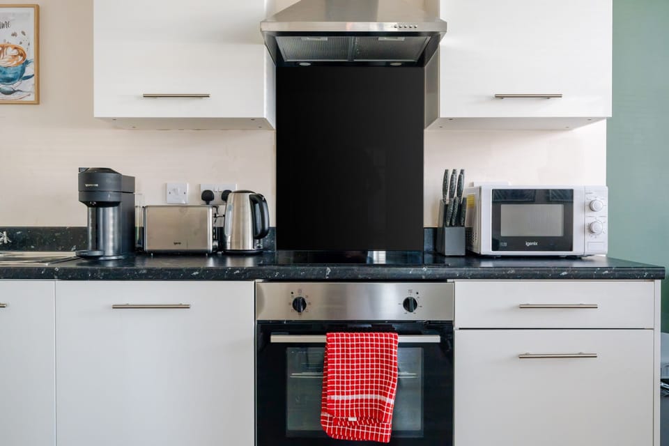Close-up of the cooking run: oven, ceramic hob, extractor and black glass splashback
