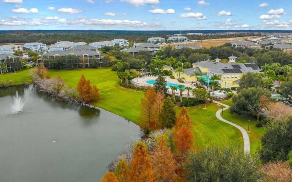 Scenic community view with lake, walking paths, and resort-style pool