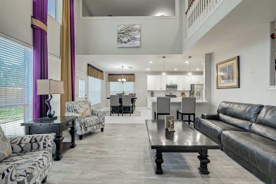 Bright open-concept living area with high ceilings, cozy seating, and a view into the modern kitchen.