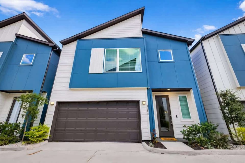 Exterior: Modern architecture with striking blue accents and lush landscaping welcomes you!