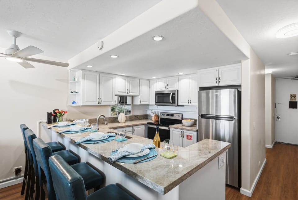 Fully equipped kitchen with breakfast bar seating in a bright, open space.