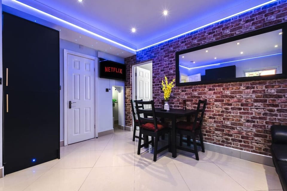 Dine beneath blue LED lighting beside the exposed brick feature wall, with a wall-mounted Netflix screen keeping you entertained over every meal.
