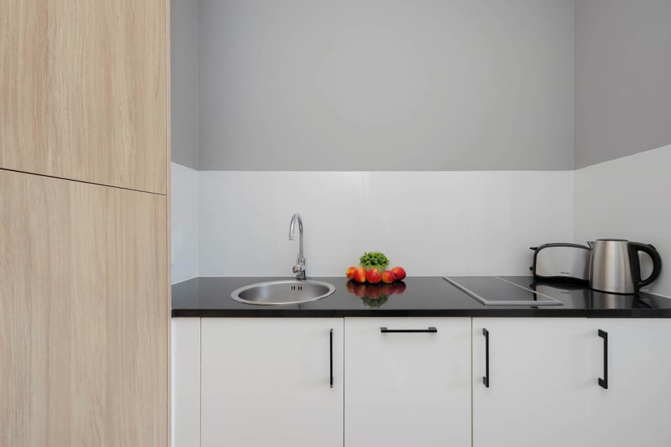 A view of the kitchenette focused on the white counter with a small plant, a coffee maker, and a tea towel.