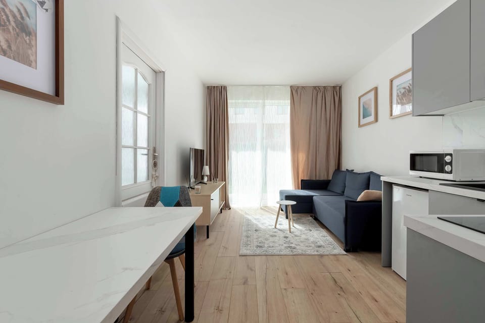 A narrow view combining a kitchen and living area, with a long countertop leading toward a seating space.