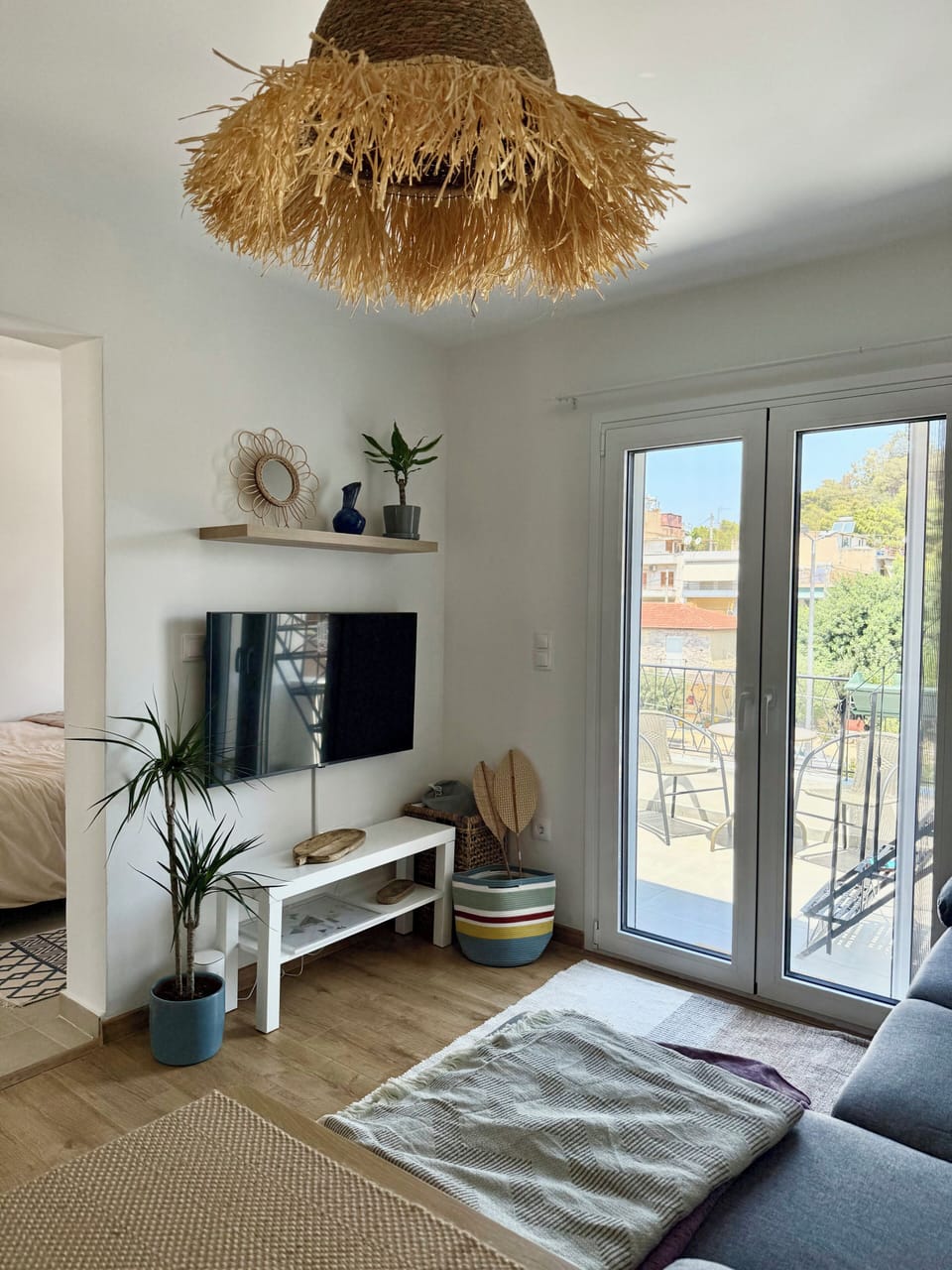 Cozy and bright living room with comfortable sofa, smart tv, and balcony view.