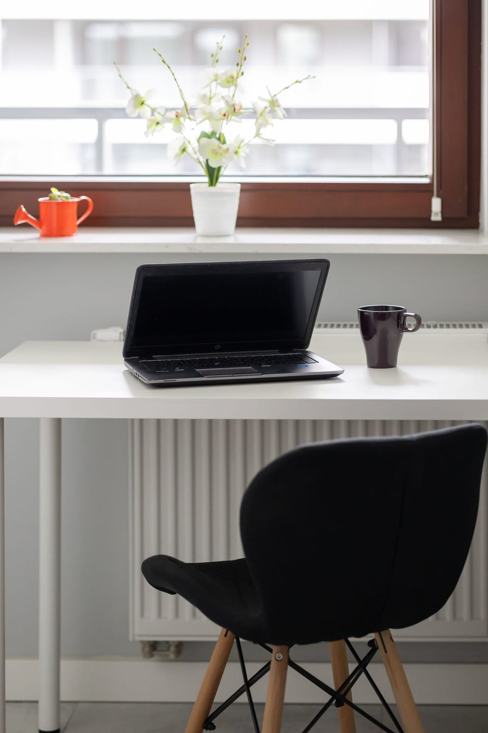 A compact workspace with a desk and a modern chair positioned against a light-colored wall. The setup is simple yet practical, ideal for remote work or studying.