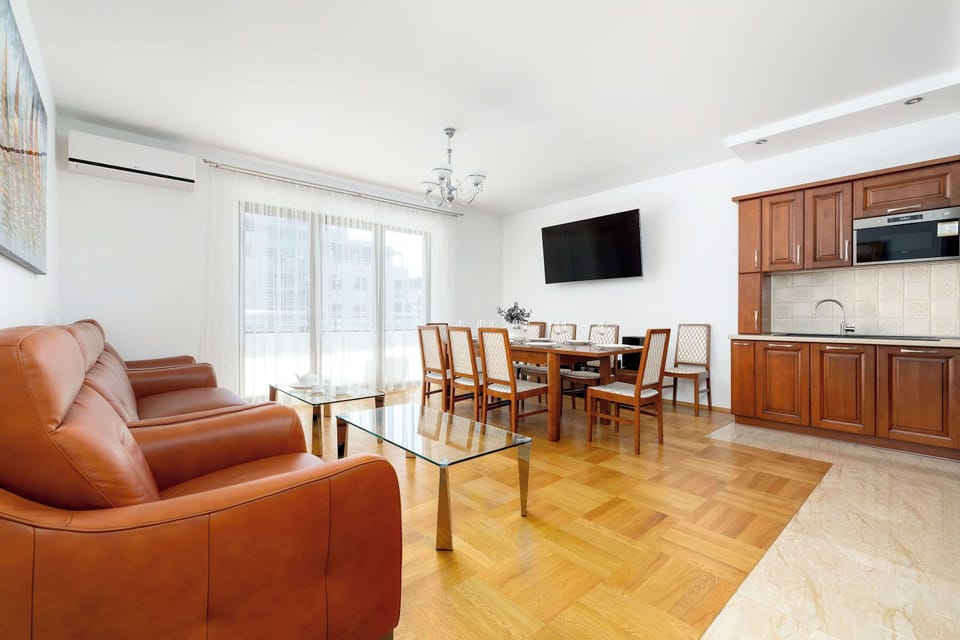 This perspective highlights the air conditioning unit mounted above the balcony door, ensuring comfort during warmer days. The flow between the living area and the kitchen is seamless and practical.
