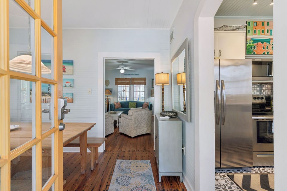 Relax in this bright coastal home where hardwood floors guide you from kitchen to cozy living room with charming beach-themed artwork throughout.
