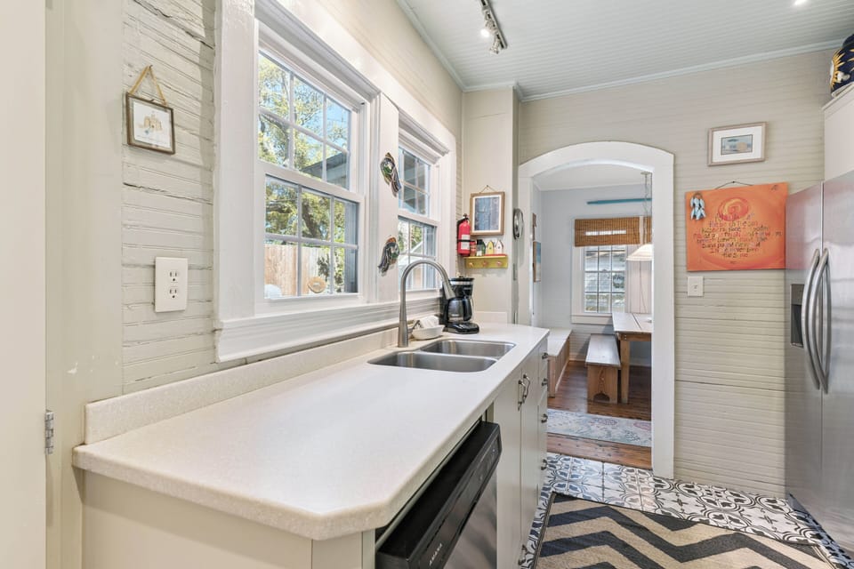 Your charming cottage kitchen welcomes you with pristine counters, farmhouse windows, and thoughtful touches that make cooking feel like home.