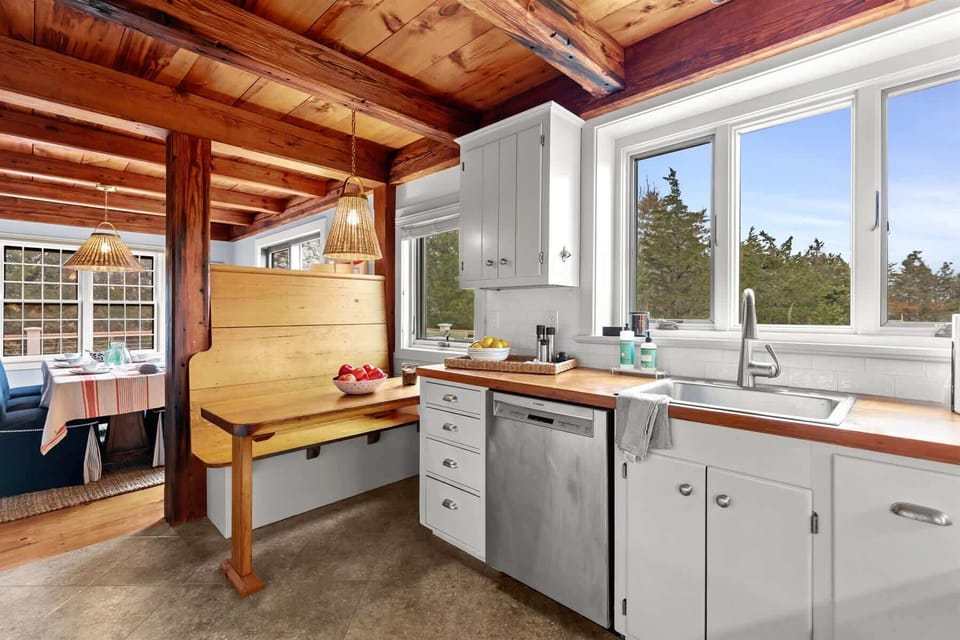 Kitchen banquette and sink area add charm and function, with beautiful natural light and warm wood accents throughout.