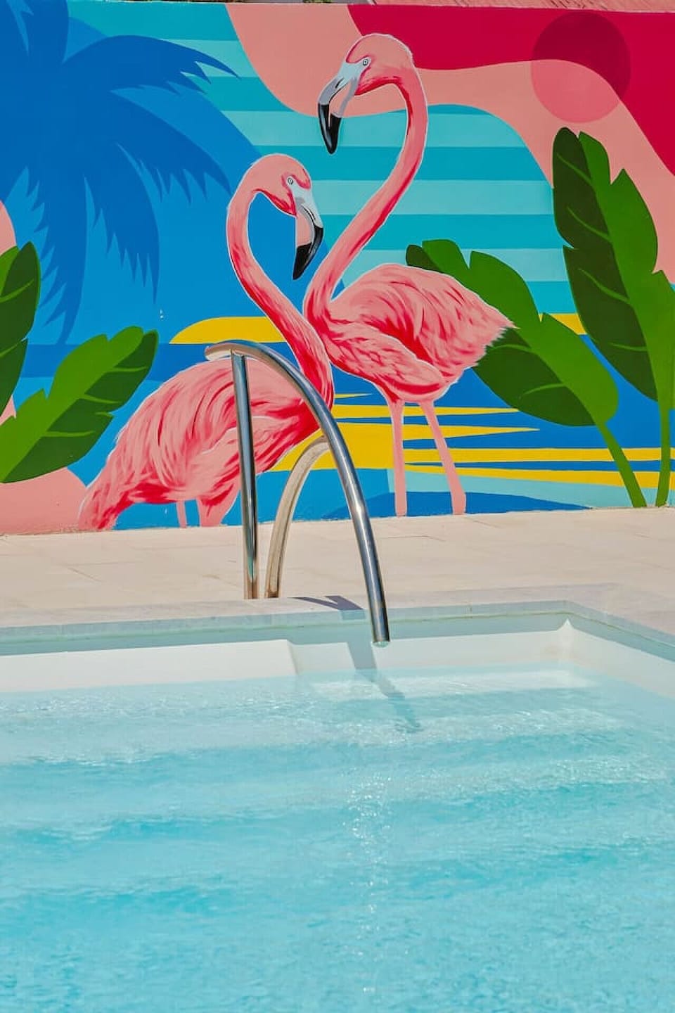 Relax by the sparkling private pool on comfortable sun loungers, surrounded by lush greenery and vibrant tropical murals—your own slice of paradise.
