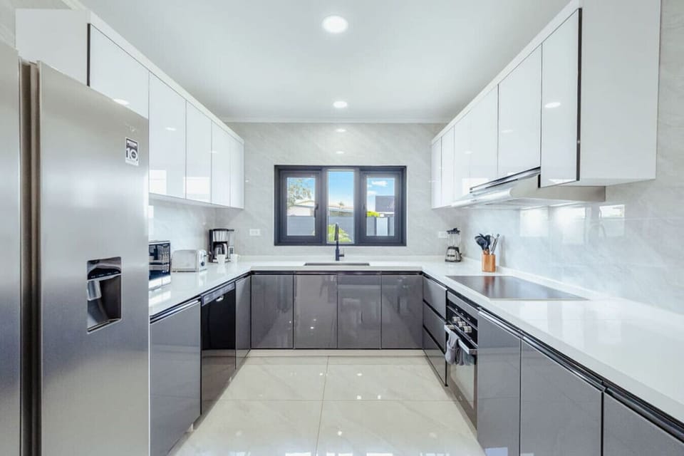 Bright and spacious modern kitchen with sleek cabinetry, high-end appliances, and a stylish breakfast bar with seating—perfect for cooking, dining, and gathering.