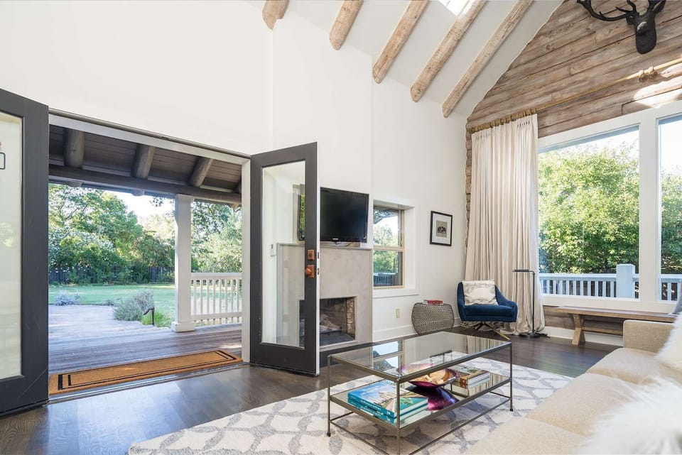 Bright, vaulted living space with rustic beams and seamless indoor-outdoor flow - open the doors to the deck and unwind in a light-filled, serene retreat.