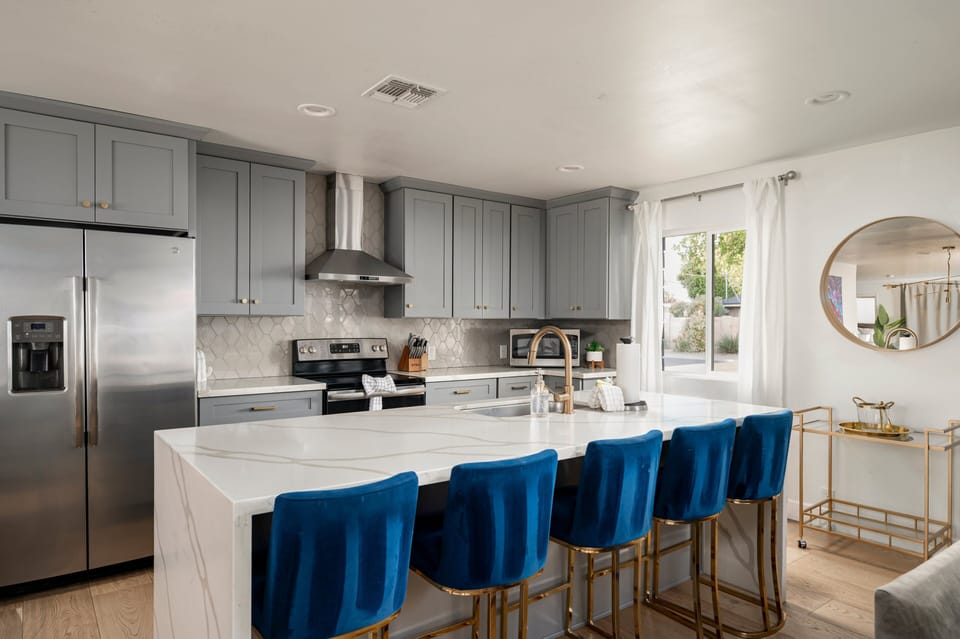 This modern kitchen features sleek finishes, stainless steel appliances, and a spacious island with plush bar seating—perfect for morning coffee, group dinners, or evening drinks.