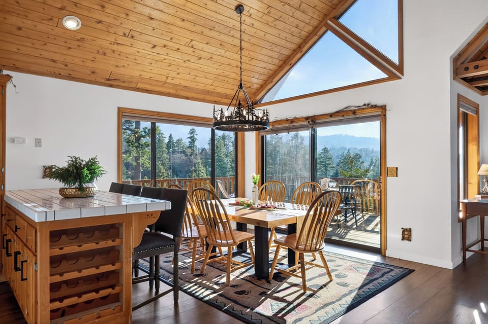 Cozy cabin dining area with wood‑beam ceilings, nature‑inspired lighting, and mountain views through large windows.