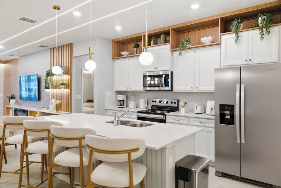 Discover a bright, airy kitchen with sleek white cabinets and warm wooden accents, perfect for gatherings. The spacious island with stylish bar stools invites leisurely breakfasts, while modern appliances enhance every meal.