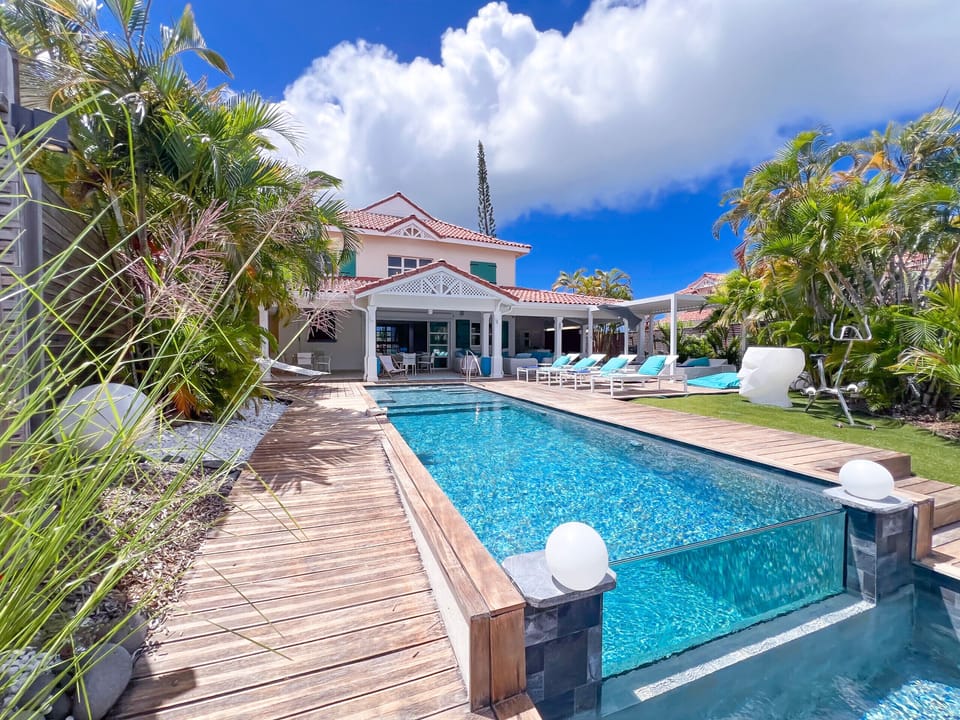 Exterior view of the pool with a glass wall and the wooden deck at Villa Belle Bleue in Saint-François.