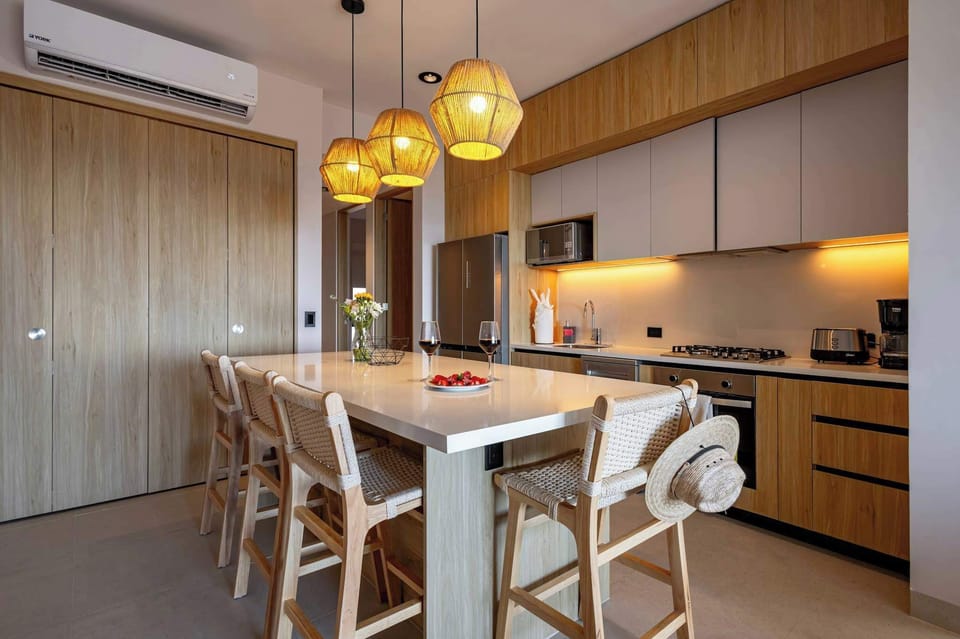 Warm dining area w/ wood table, woven chairs & pendant lighting for relaxed shared meals