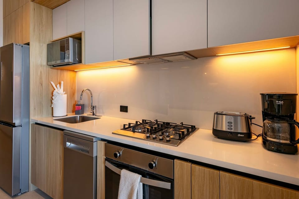 Sleek kitchen w/ modern cabinetry, cooktop & warm under-cabinet lighting